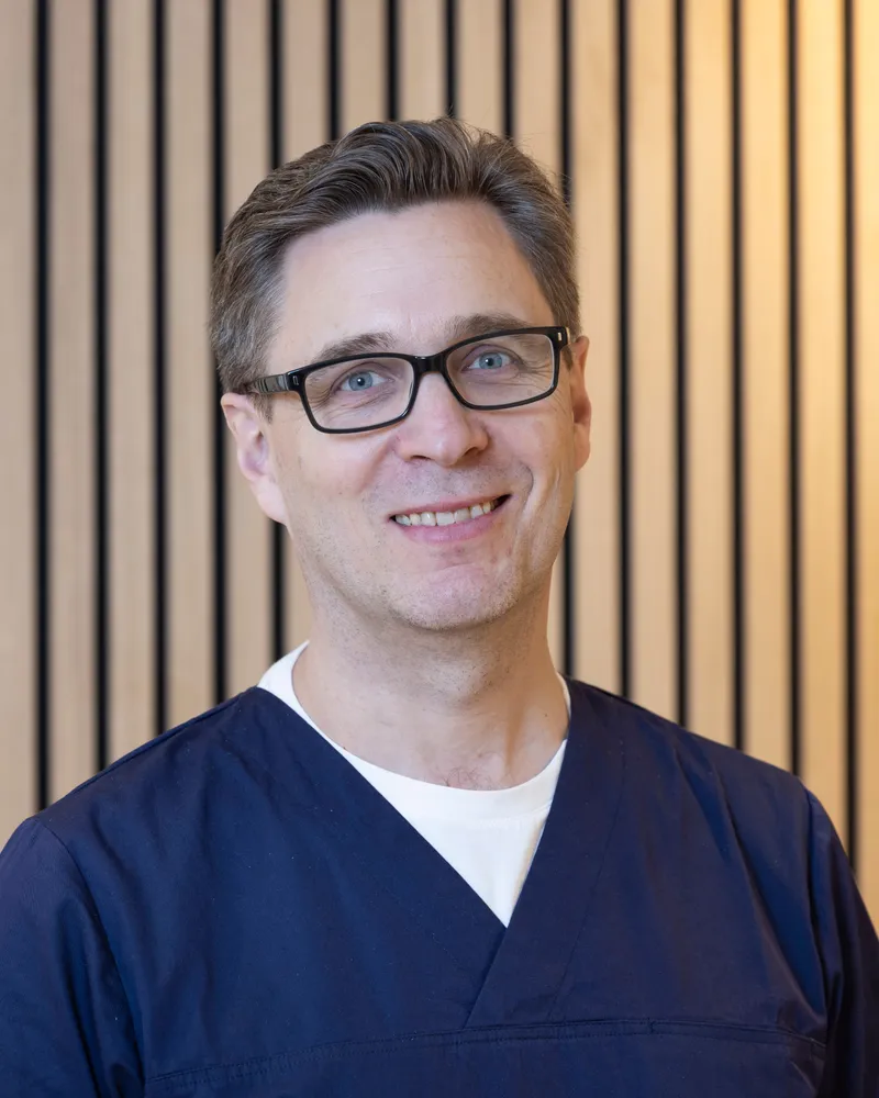 Porträt von Dr. med. Stefan Noster vor heller Holzwand